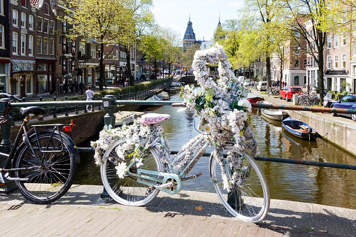 Bicycle decorated with white flowers parked on the corner of the Prinsengracht (Prince's Canal) and the Spiegelgracht (Mirror's canal) in Amsterdam. The famous Rijksmuseum is visible in the background.
