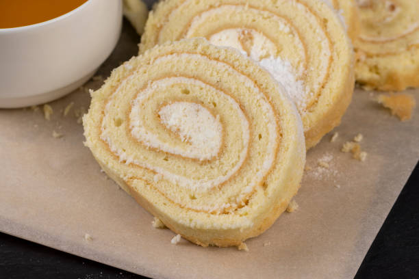 sweet dessert with cottage cheese cream and soft sponge cake, twisted dessert curd roll of soft sponge cake with cream cream in powdered sugar