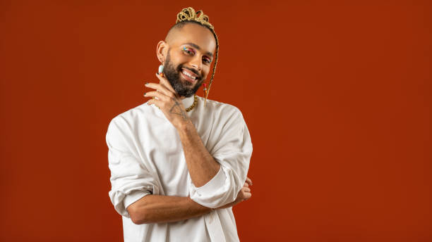 Make up artist Black latin gay man isolated on red background Make up artist. Black afro-american gay man with bright make-up in white clothes smiling looking at camera isolated on red background studio portrait Fashion makeup lgbt concept. Banner format queer man facing camera stock pictures, royalty-free photos & images