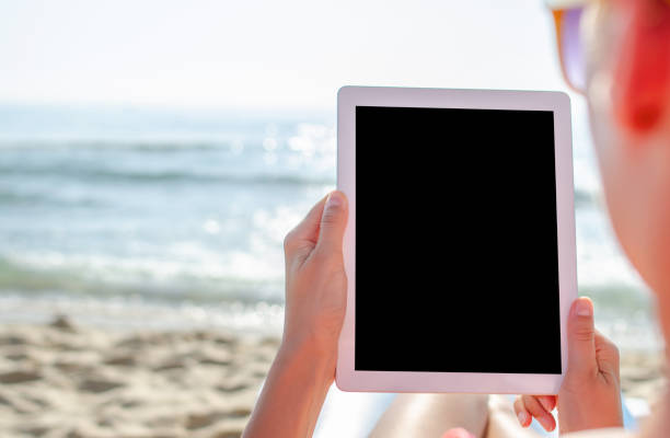 istock Woman with a tablet pc or smartphone on the beach. 1489535080