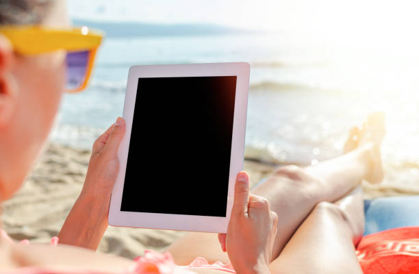 istock Woman with a tablet pc or smartphone on the beach. 1489535083