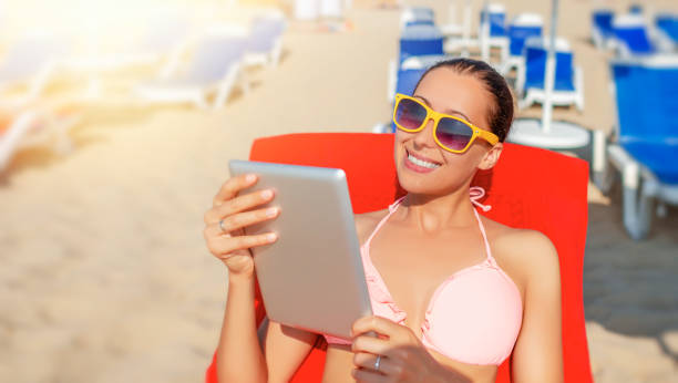 istock Woman with a tablet pc or smartphone on the beach. 1489535084