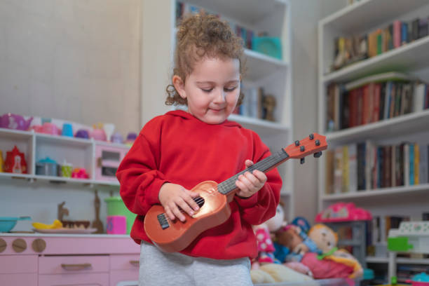 Little Curly Haired Girl Singing and Playing Ukulele