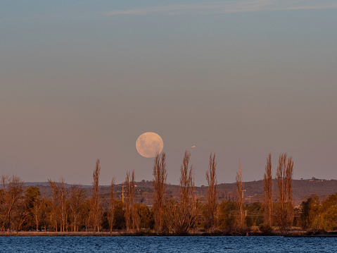 Moon rise over Lake Burley Griffith in Canberra and small plane flying