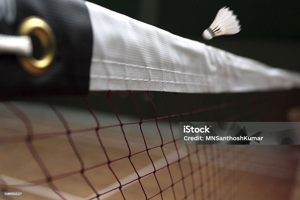 Shuttle badminton net up close and a fast moving shuttlecock Photo of shuttle badminton net up close and a fast moving shuttlecock above the net in a indoor badminton court Badminton - Sport Stock Photo