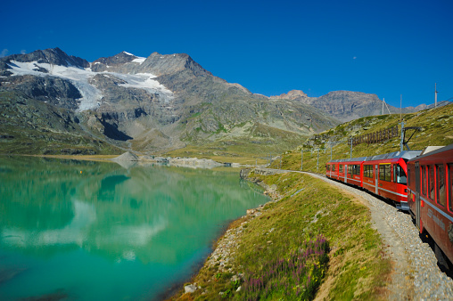 Sankt Moritz Switzerland May 13 2023: Little red train traveling in the Swiss mountains and connecting Switzerland with Italy