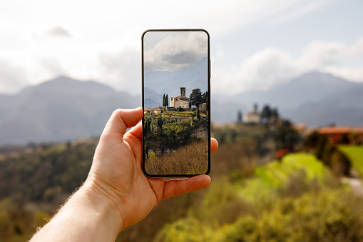 Travel photography: The tourist takes a photo of the beautiful Italian landscape using a mobile phone