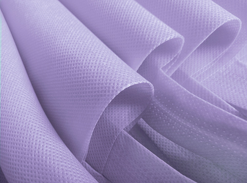 purple polypropylene bag. non-woven fabric with wavy pleats. pile of environmentally friendly bag materials. spunbond bag