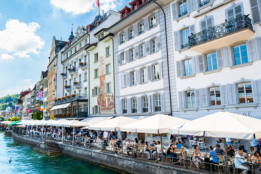 Lucerne, Switzerland - July 10, 2022: Rathausqui is the pedestrian walkway on the riverfront of the Reuss River with many quaint hotels, cafes and bars. Very popular tourist destination in Lucerne