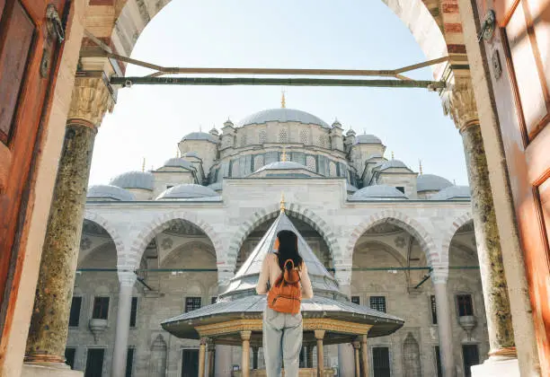 Photo of A young female traveler with a backpack on her back walks towards the Fatih Mosque in Istanbul