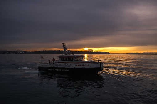 Seattle, USA - Nov 23, 2022: Sunset on Elliott Bay with a Seattle Fire boat by the Seattle Aquarium.