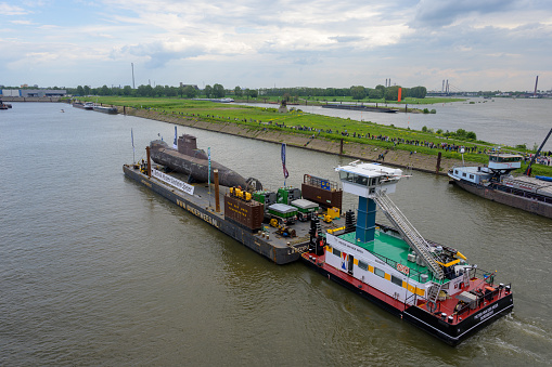 Aerial view of the red Tugboat pushing a heavy barge on the Danube river.