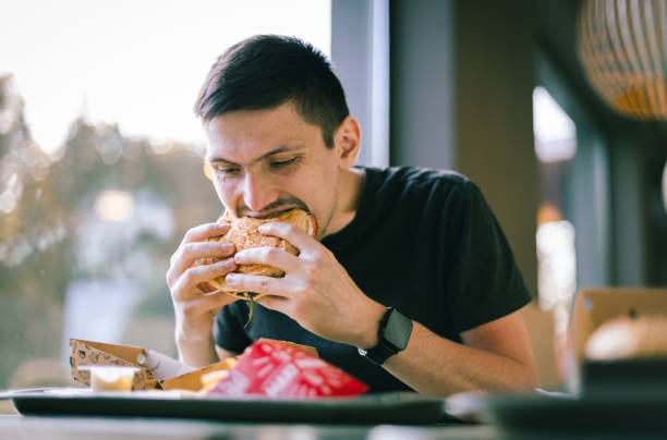 istock A young man eats fast food at a diner. 1489581005