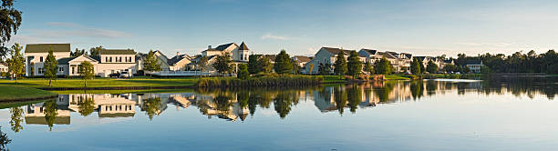 Luxury lake shore homes reflected Large luxury homes in a picturesque panoramic setting reflecting in the still blue waters of this Florida lake as the warm light of the sun illuminates their traditional wooden designs. ProPhoto RGB profile for maximum color fidelity and gamut. kissimmee stock pictures, royalty-free photos & images