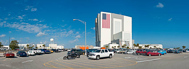 Vehicle Assembley Building Cape Canaveral Big blue panoramic Florida skies over the Vehicle Assembly Building at the NASA Kennedy Space Center, Cape Canaveral. The world's largest single storey building, the VAB can be seen for miles around across the flat landscape of the Atlantic coast. The two doors on the left were for the exit of the Saturn V Apollo rockets, whilst the Shuttle on its crawler transporter exits vertically on the right toward the launch pads several miles away. ProPhoto RGB profile for maximum color fidelity and gamut. nasa kennedy space center photos stock pictures, royalty-free photos & images