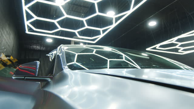 Process of applying a protective PPF film to a car. Wide shot of Hands of a professional applying a protective film of laminate.
