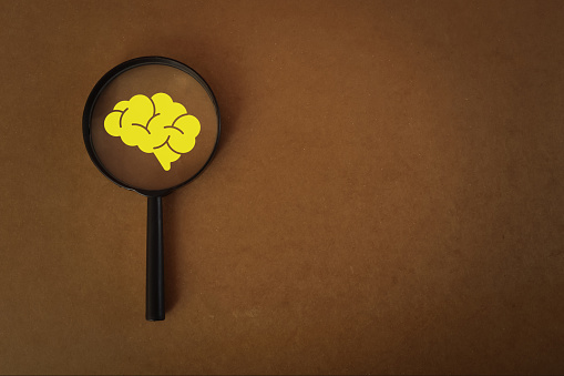 Magnifying glass with human brain symbol.The idea of different thinking acknowledges the diversity of thought processes, including rational and irrational thinking.