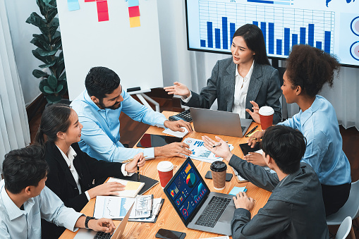 Multiracial analyst team use BI Fintech software to analyze financial data on meeting. Top view finance dashboard data display on laptop screen with analyzed chart for marketing indication. Concord