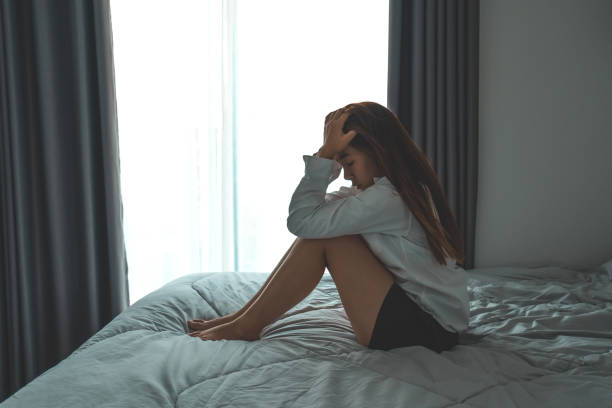 istock Depressed woman sitting head in hands in the bedroom with low light environment dramatic concept 1489598309