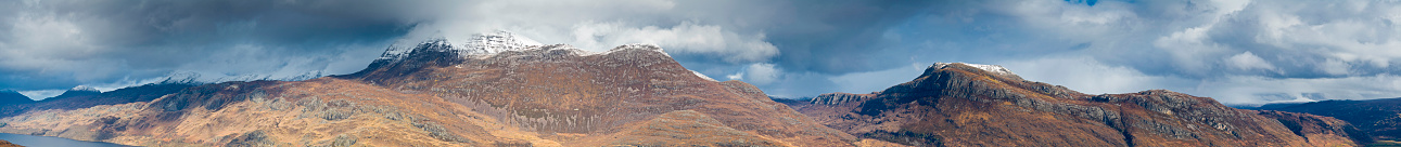 Very large and very detailed panoramic vista across the wild snow capped peak of Beinn Airigh Charr and the dramatic rocky summit of Slioch overlooking Loch Maree deep in the remote Highland wilderness of Wester Ross, Scotland. ProPhoto RGB profile for maximum color fidelity and gamut.
