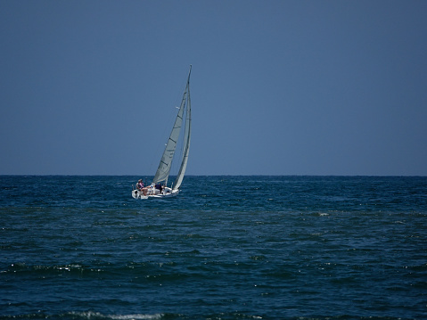 Nuevo Vallarta, Nayarit, Mexico- April 19, 2023: Sailboat leaning into the wind and sailing away near the horizon.