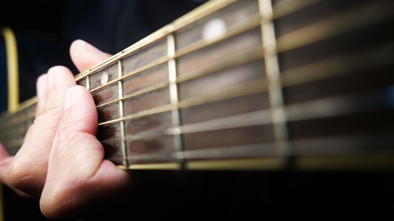 Guitarist with his guitar. Music time. Guitarist playing guitar. Man playing chords. Singer in a soundproof music studio. Guitar strings. Musicians at studio. Guitar chords. Neck of the guitar. Fretboard, close-up shot. Artist playing. Recording music. Man playing a guitar. Acoustic guitar, close-up angle. Musical instrument in a studio. Musician in a recording studio room.