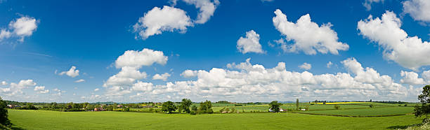 Big blue summer skies green farms Panoramic blue sky and white fluffy clouds over lush green fields, pasture and farmland, rolling hills and picturesque patchwork landscape. ProPhoto RGB profile for maximum color fidelity and gamut. patchwork landscape stock pictures, royalty-free photos & images