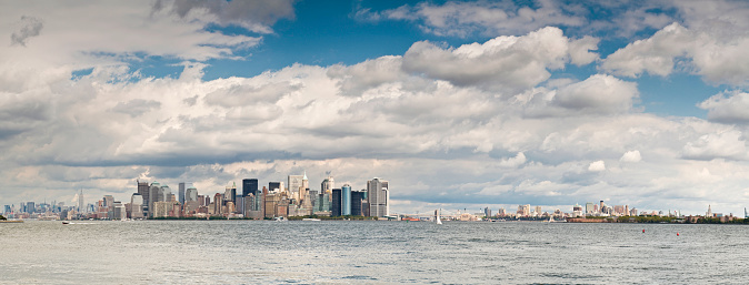 Panoramic vista across the calm waters of New York Harbor from the Hudson River and the towers of Midtown past the skyscrapers of the downtown financial district of Lower Manhattan, Battery Park and the Staten Island ferry to the Brooklyn Bridge, East River and Governers Island. ProPhoto RGB profile for maximum color fidelity and gamut.