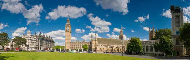 Big blue summer skies with white fluffy clouds over the iconic cityscape around Parliament Square, Westminster, London, from Whitehall, past Portcullis House, Big Ben, St Stephen's Tower and the ornate gothic exterior of the Houses of Parliament to the tower of St. Margaret's in front of Westminster Cathedral. ProPhoto RGB profile for maximum color fidelity and gamut.