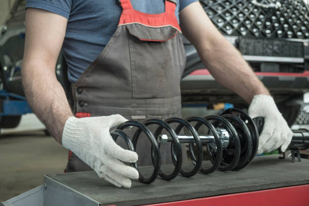 An auto mechanic holds a new shock absorber strut and a spring in his hands. The specialist evaluates the compatibility of the car suspension parts. Car maintenance. shock absorber stock pictures, royalty-free photos & images