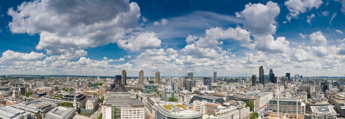Blue skies and dramatic cloudscape over the skyscrapers and canyons of the City of London, from the Barbican, past the Bank of England and landmark towers of the downtown district, across the River Thames to City Hall. ProPhoto RGB profile for maximum color fidelity and gamut.