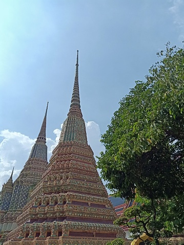 Wat Pho (Thai: วัดโพธิ์, pronounced also spelled Wat Po, is a Buddhist temple complex in the Phra Nakhon District, Bangkok, Thailand. It is on Rattanakosin Island, directly south of the Grand Palace. Known also as the Temple of the Reclining Buddha, its official name is Wat Phra Chetuphon Wimon Mangkhalaram Rajwaramahawihan (Thai: วัดพระเชตุพนวิมลมังคลารามราชวรมหาวิหาร; pronounced. The more commonly known name, Wat Pho, is a contraction of its older name, Wat Photaram (Thai: วัดโพธาราม; Wat Photharam).\n\nPhra Chedi Rai - Outside the Phra Rabiang cloisters are dotted many smaller chedis, called Phra Chedi Rai. Seventy-one of these small chedis were built by Rama III, each five metres in height. There are also four groups of five chedis that shared a single base built by Rama I, one on each corner outside the cloister. The 71 chedis of smaller size contain the ashes of the royal family, and 20 slightly larger ones clustered in groups of five contain the relics of Buddha.