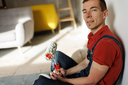 Photo of mature man house painter sitting on the floor while taking a break at work