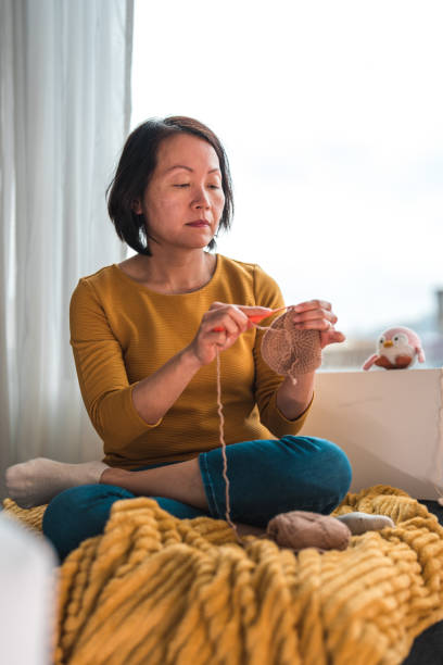 istock Focused Mid Adult Asian Woman Knitting on Sofa 1489645708