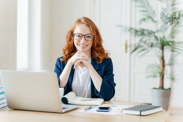 istock Working concept. Intelligent manager with satisfied expression, writes in notepad, works on modern laptop computer, uses organizer app, sits against office interior. Experienced entrepreneur 1489646778