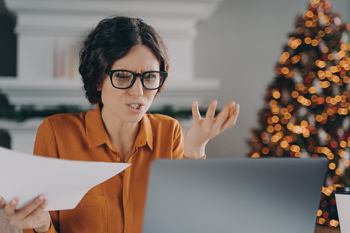 Stressed Italian businesswoman feels angry with error or mistake while remotely working on Christmas