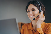 Pleasant woman Spanish speaking call center employee in wireless headset talking with client