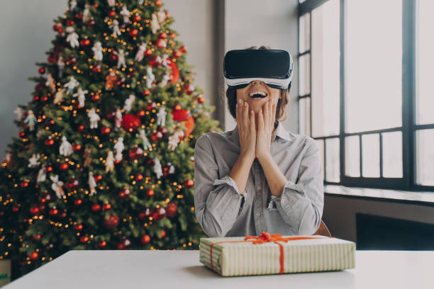 istock Amazed excited young woman wearing virtual reality goggles sitting against xmas tree 1489649708