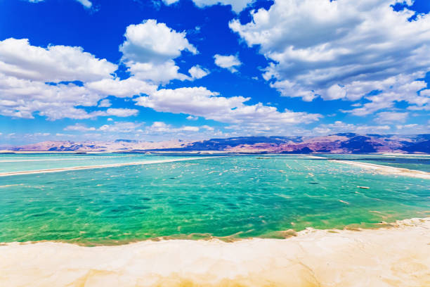 Picturesque Dead Sea. Bright March day. The water reflects the bright blue of the sky. Lush cumulus clouds are reflected in the water. Drone footage.