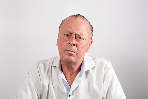 Serious man with white shirt having doubts and with confuse face expression on isolated white background