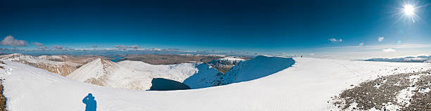 Summit sunburst snow shadow scene Bright sunlight flaring over the crisp white winter landscape, snowy cornices and rocky ridges of the high summit of Helvellyn in the heart of the Lake District National Park, Cumbria, UK. ProPhoto RGB profile for maximum color fidelity and gamut. striding edge stock pictures, royalty-free photos & images