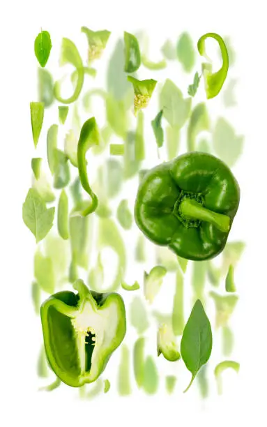 Abstract background made of Green Pepper vegetable pieces, slices and leaves isolated on white.