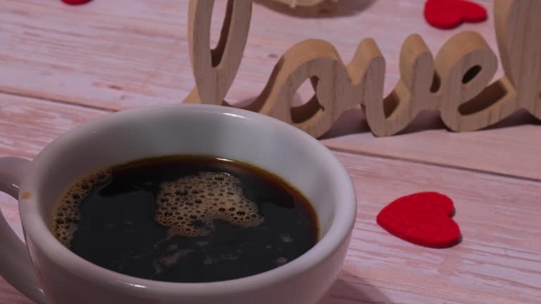 Wooden word love with heart romance with pouring coffee to white coffee cup. Minimal concept of greeting card for Valentine's Day, Mother's Day, Women's Day Festive holiday card concept