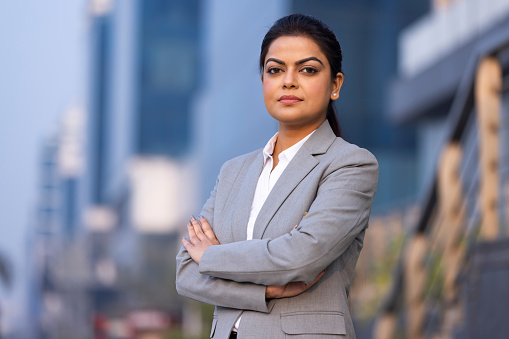 Portrait of young businesswoman with crossed arms standing outside the office.