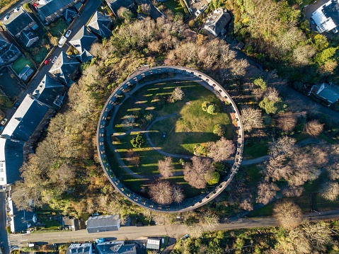 A bird's-eye view of a lush, circular park surrounded by a ring of towering trees and tall buildings