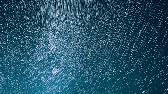 Hyper Trails Of Stars. Bewitching Illusion Of Star Trails. Star And Meteoric Trails On Night Sky Background. Spin Of Unusual Amazing Stars Effect In Sky. Rotate Of Sky Background. Large Exposure. Meteors Cross Dark Blue Sky. .