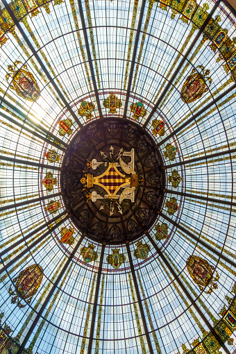 Valencia, Spain - July 14, 2022: The magnificent dome of the Mercado Central Market, viewed from below, emphasizing its intricate details and indoor perspective. No people are on the scene.