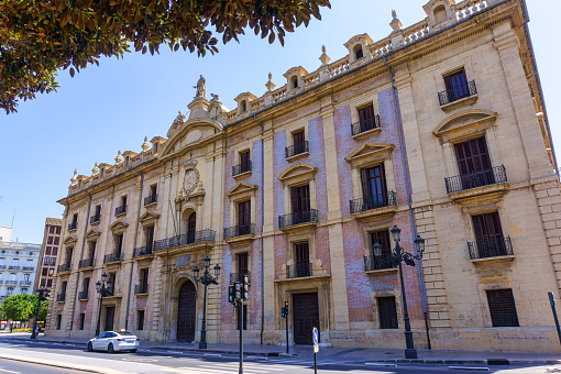 Valencia, Spain - July 14, 2022: Low-angle view of the Supreme Justice Tribunal's façade, with a white car parked in front of the building during the daytime. There are no people on the scene.