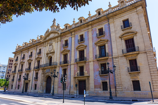 Valencia, Spain - July 16, 2022: Low-angle view of the Supreme Justice Tribunal facade during the daytime. The blue sky is visible above, and no people are on the scene.