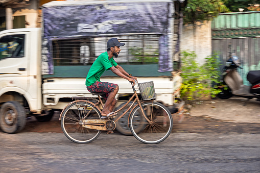 Negombo, North Central Province, Sri Lanka - March 4th 2023:  Man in a green shirt on a woman's bike in the center of the city